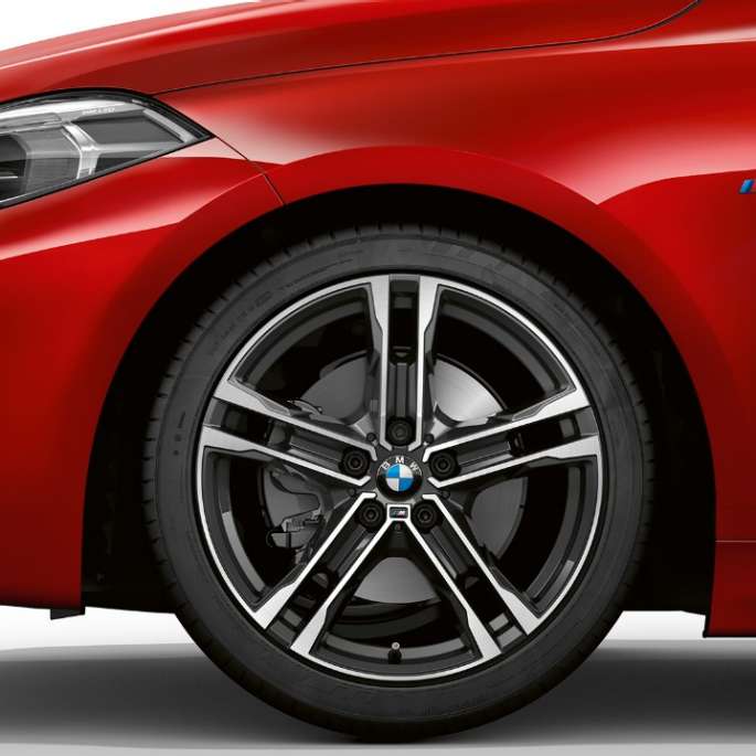 BMW 1 серии модель M Sport, спереди сбоку. BMW 1 серии модель M Sport в Melbourne Red металлик, спереди сбоку с 17-дюймовыми легкосплавными дисками M с двойными спицами, стиль 550 M, двухцветные.