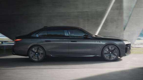 Запас хода на электротяге, BMW M760e xDrive G70, пакет M Performance Запас хода на электротяге, BMW M760e xDrive G70, пакет M Performance, BMW Individual двухцветная окраска "Черный Сапфир металлик" и "BMW Individual Серый Дравит металлик", вид сбоку в движении на улице