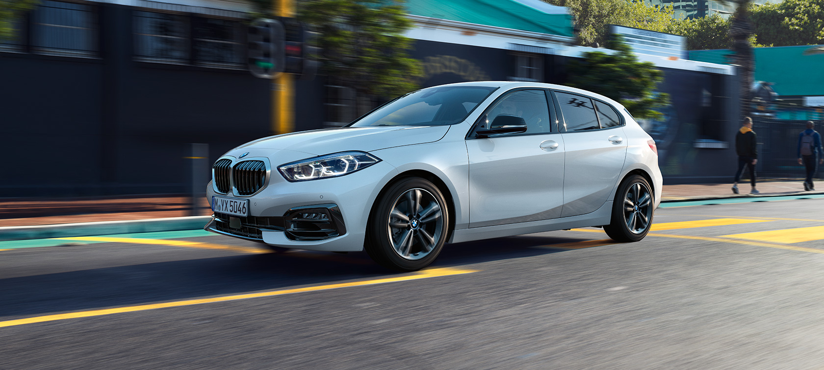 BMW 1 серии модель Sport Line, вид сбоку с поворотом в три четверти. BMW 1 серии модель Sport Line в Mineral White металлик, вид сбоку с поворотом в три четверти, за рулем.
