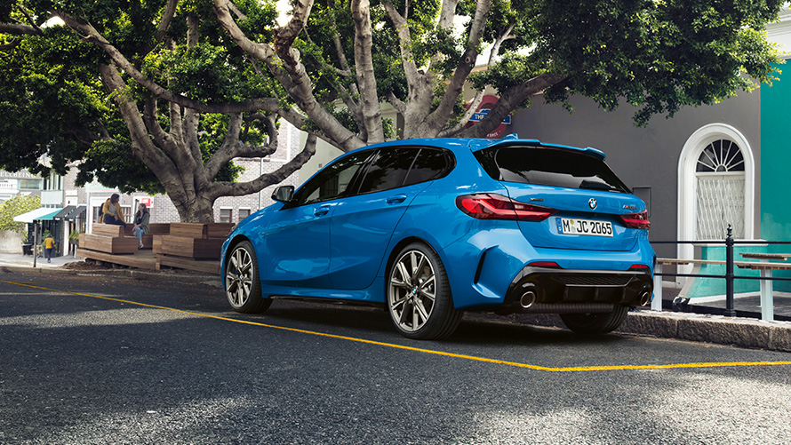 BMW 1-й серии в цвете Misano Blue металлик с высоты птичьего полета с человеком на переднем плане.