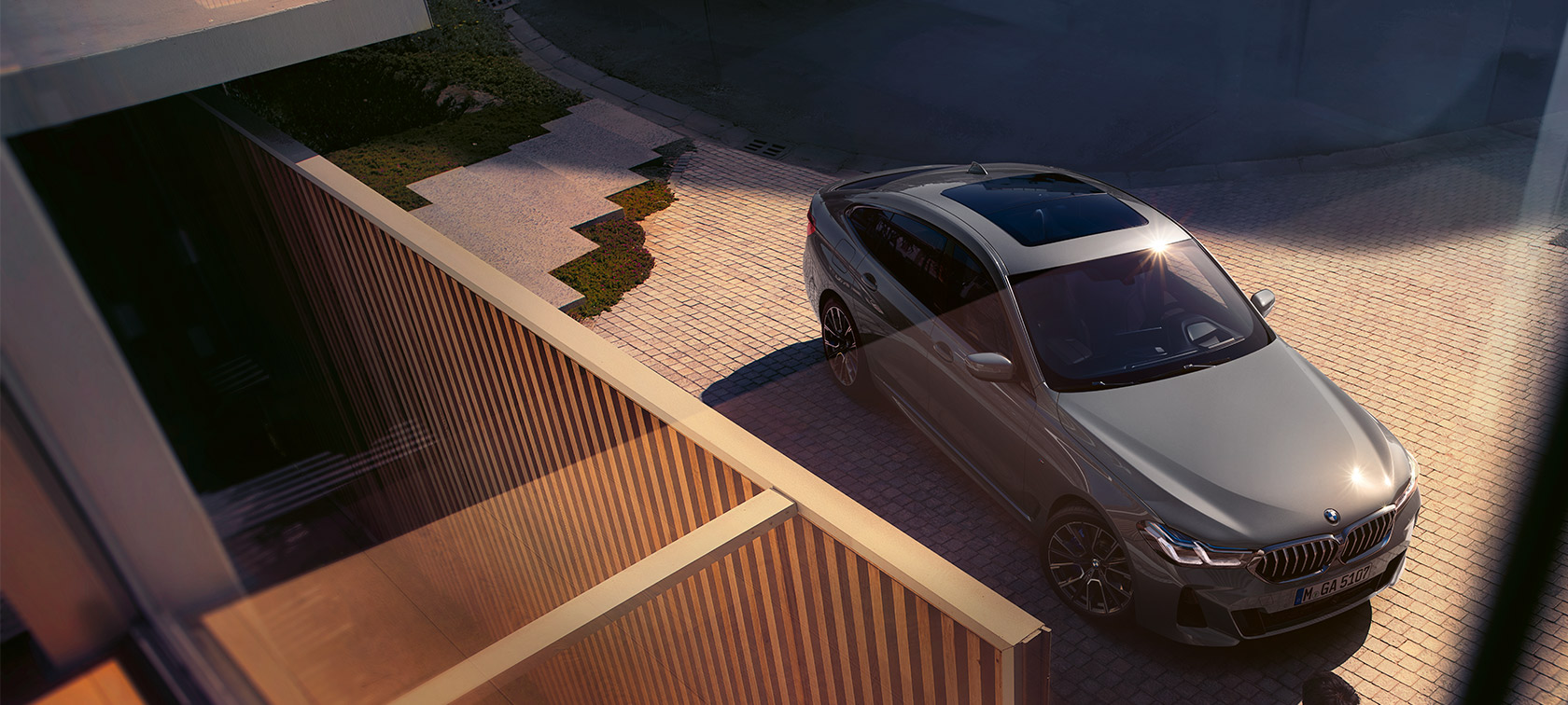 BMW 6-й серии Gran Turismo 640i xDrive (G32) серого цвета Bernina Grey BMW 6-й серии Gran Turismo 640i xDrive (G32) серого цвета Bernina Grey на фоне здания, вид спереди с поворотом в три четверти