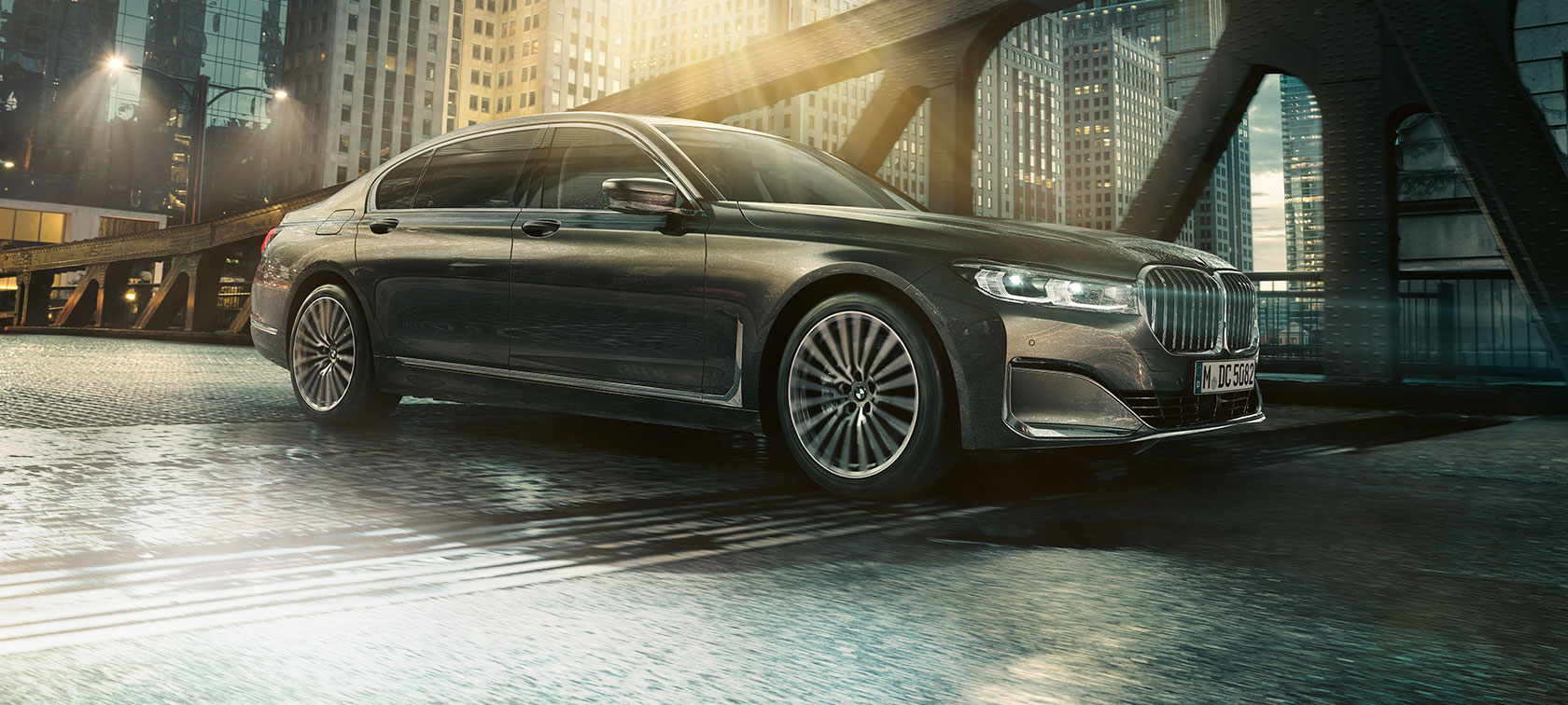 BMW 7 серии Седан: вид сбоку BMW 7 серии Седан: вид сбоку с открытой дверью на фоне освещенного здания гостиницы