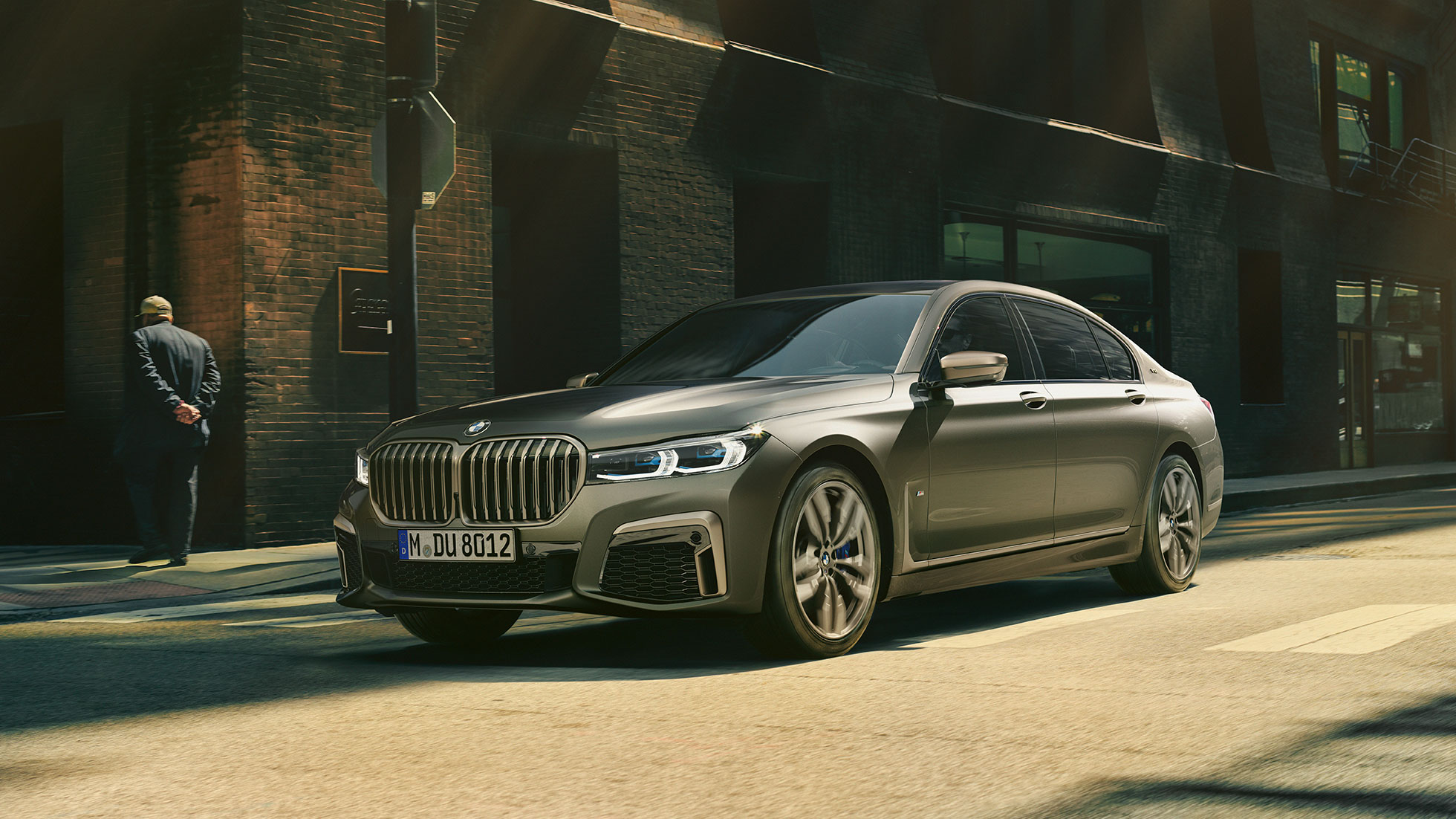 BMW M760Li xDrive в городе BMW M760Li xDrive: в движении по городским улицам, вид сзади сбоку