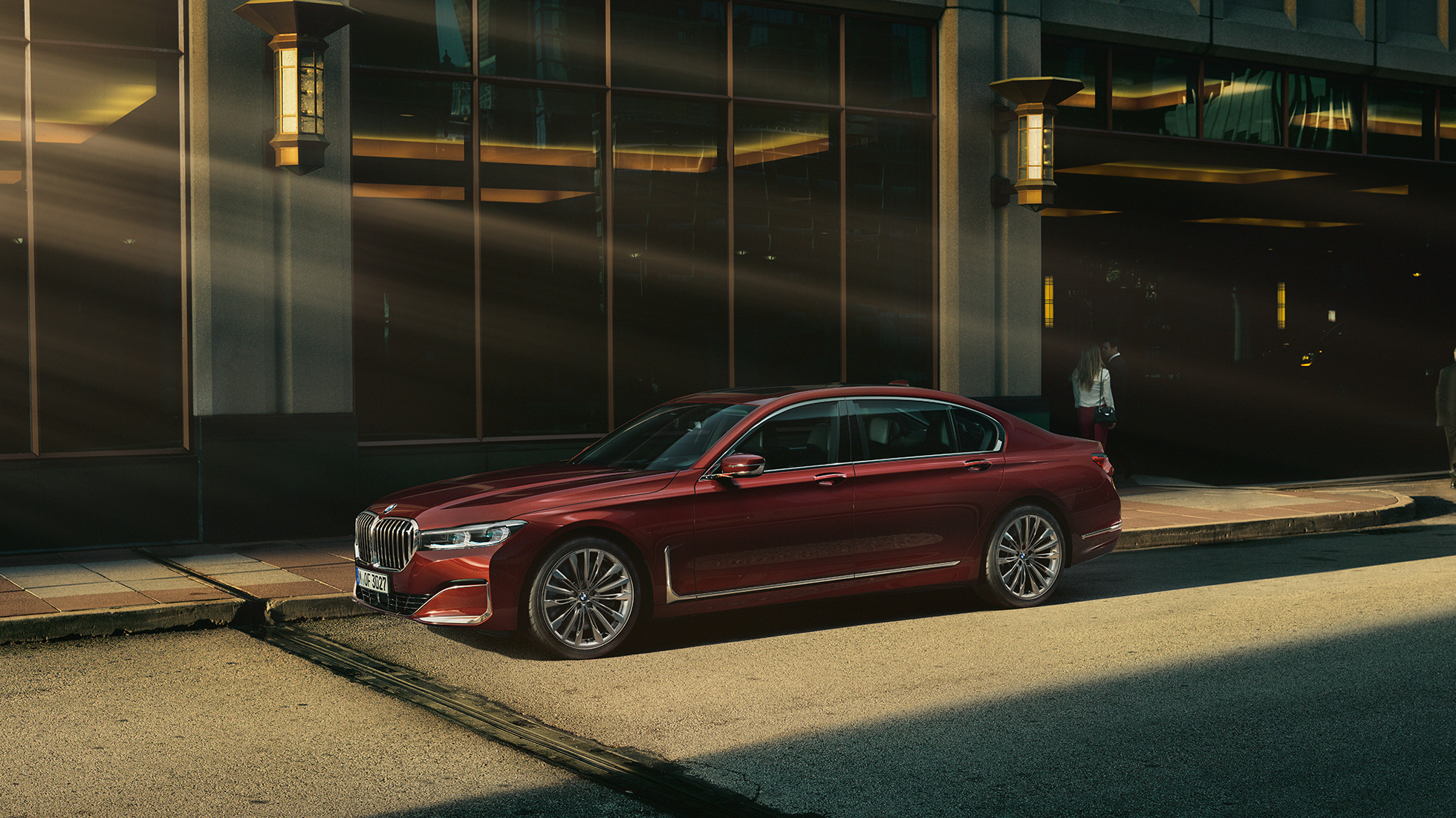 BMW 7 серии Седан Individual: вид сбоку BMW 7 серии Седан Individual красного цвета: вид сбоку на фоне городского пейзажа