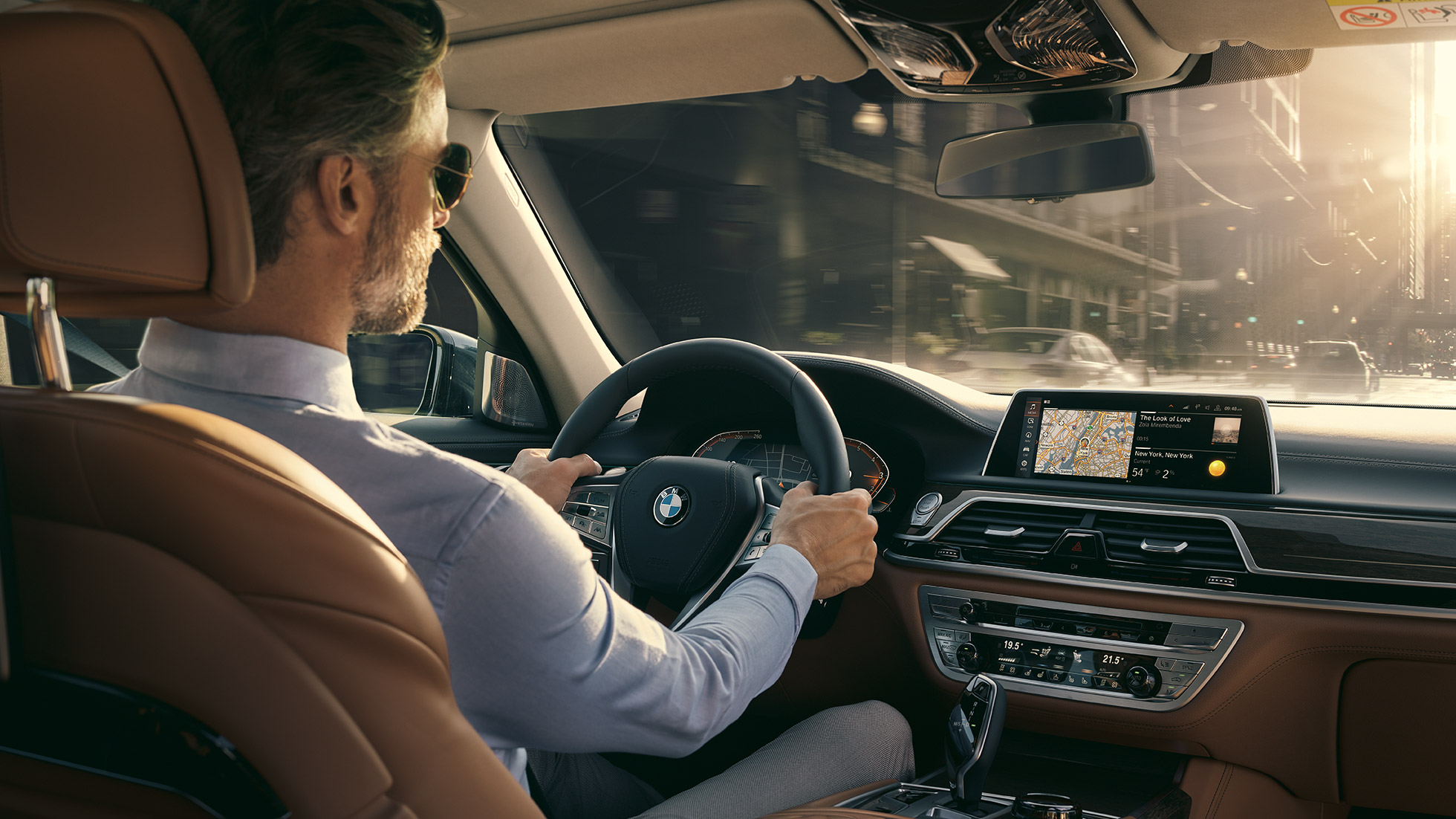 BMW 7 серии Седан: возможности подключения BMW 7 серии Седан: мужчина использует возможности подключения BMW сидя в автомобиле
