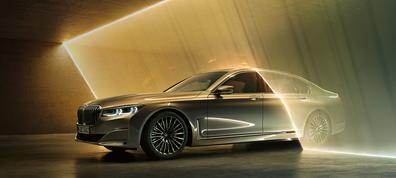 BMW 7 серии Седан: серый BMW, вид спереди с поворотом в три четверти BMW 7 серии Седан: серый BMW, вид спереди с поворотом в три четверти в окружении потоков света