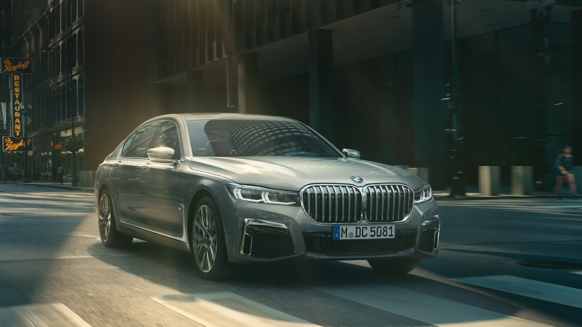 Пакет систем помощи водителю Driving Assistant Professional седана BMW 7 серии Ассистент вождения Professional: BMW 7 серии Седан в движении на фоне городского пейзажа, вид спереди с поворотом в три четверти