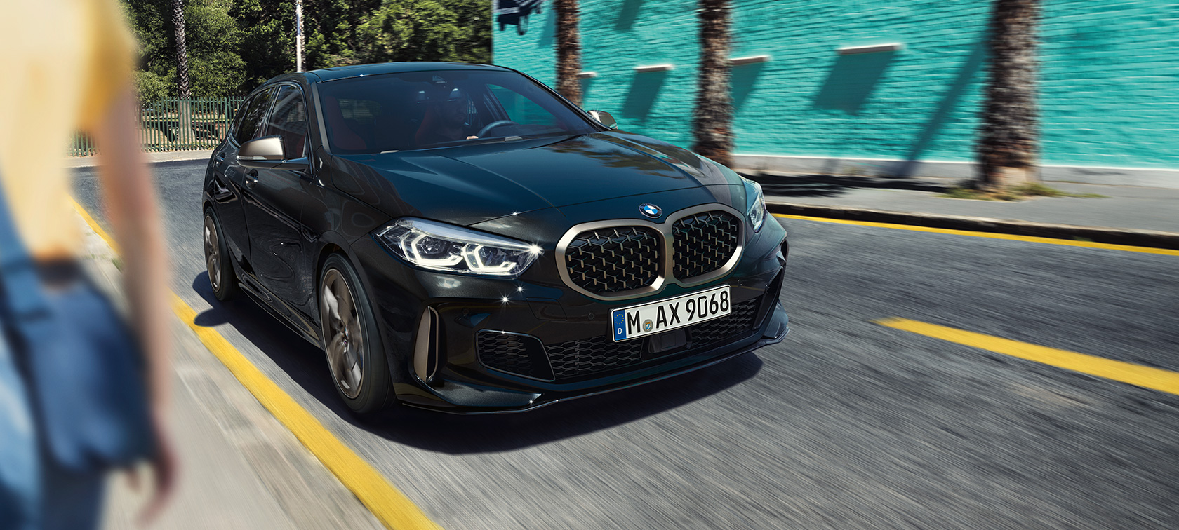 BMW M135i xDrive, вид спереди с поворотом в три четверти. BMW M135i xDrive в Black Sapphire металлик, вид спереди за рулем с поворотом в три четверти.