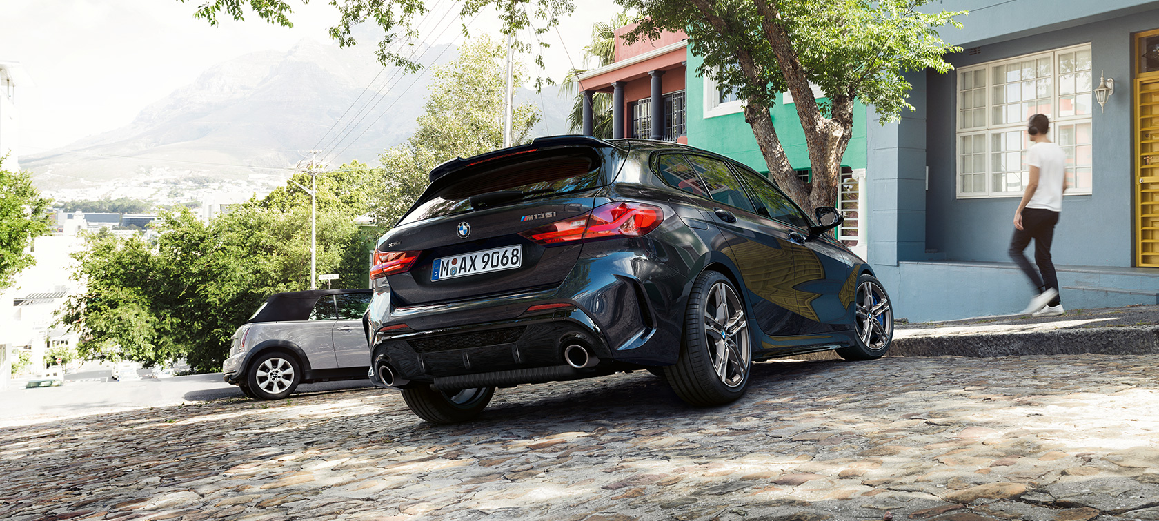 BMW M135i xDrive, вид сзади с поворотом в три четверти. BMW M135i xDrive в Black Sapphire металлик, вид сзади с поворотом в три четверти, парковка перед жилым зданием.