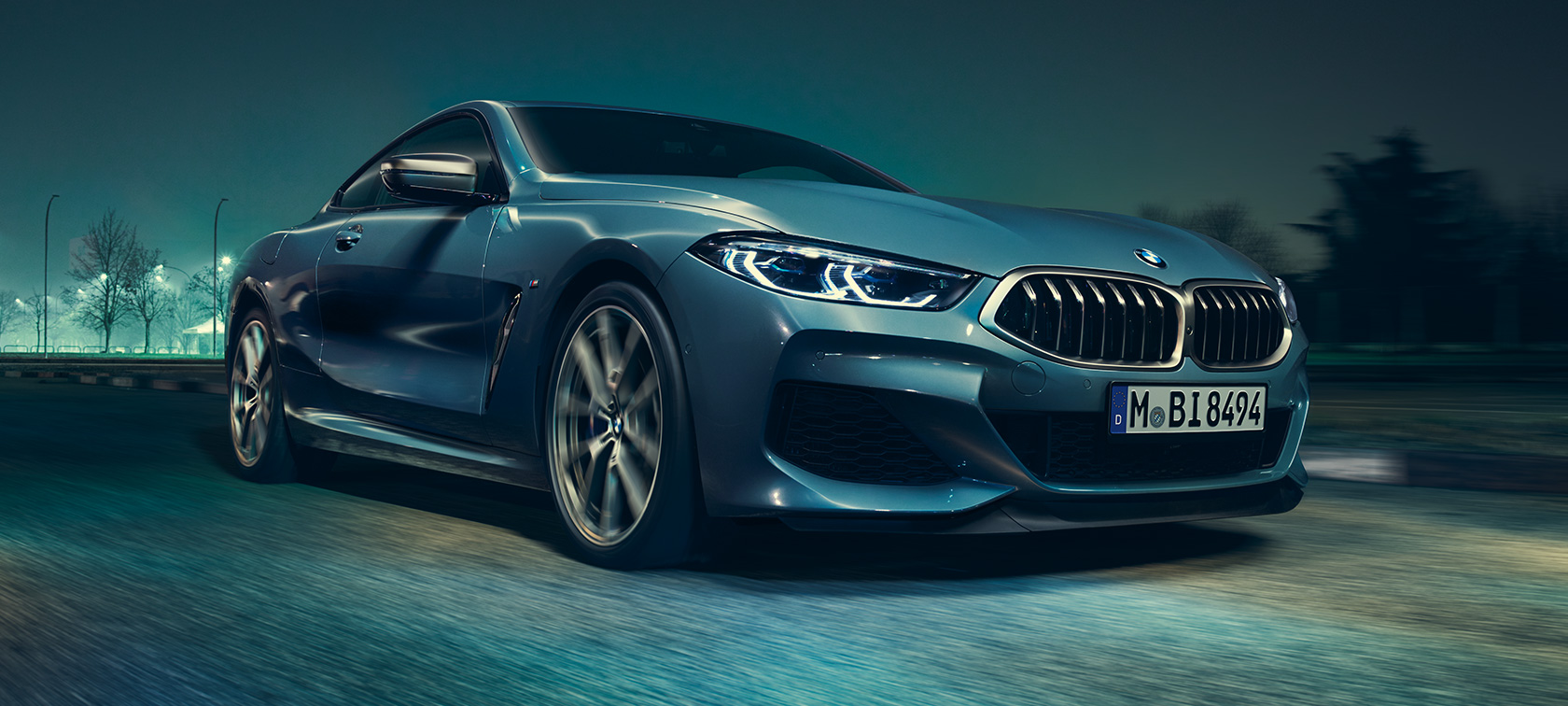 BMW M850i xDrive Coupé, вид спереди с поворотом в три четверти. BMW M850i xDrive Coupé в Barcelona Blue металлик за рулем, вид спереди с поворотом в три четверти.