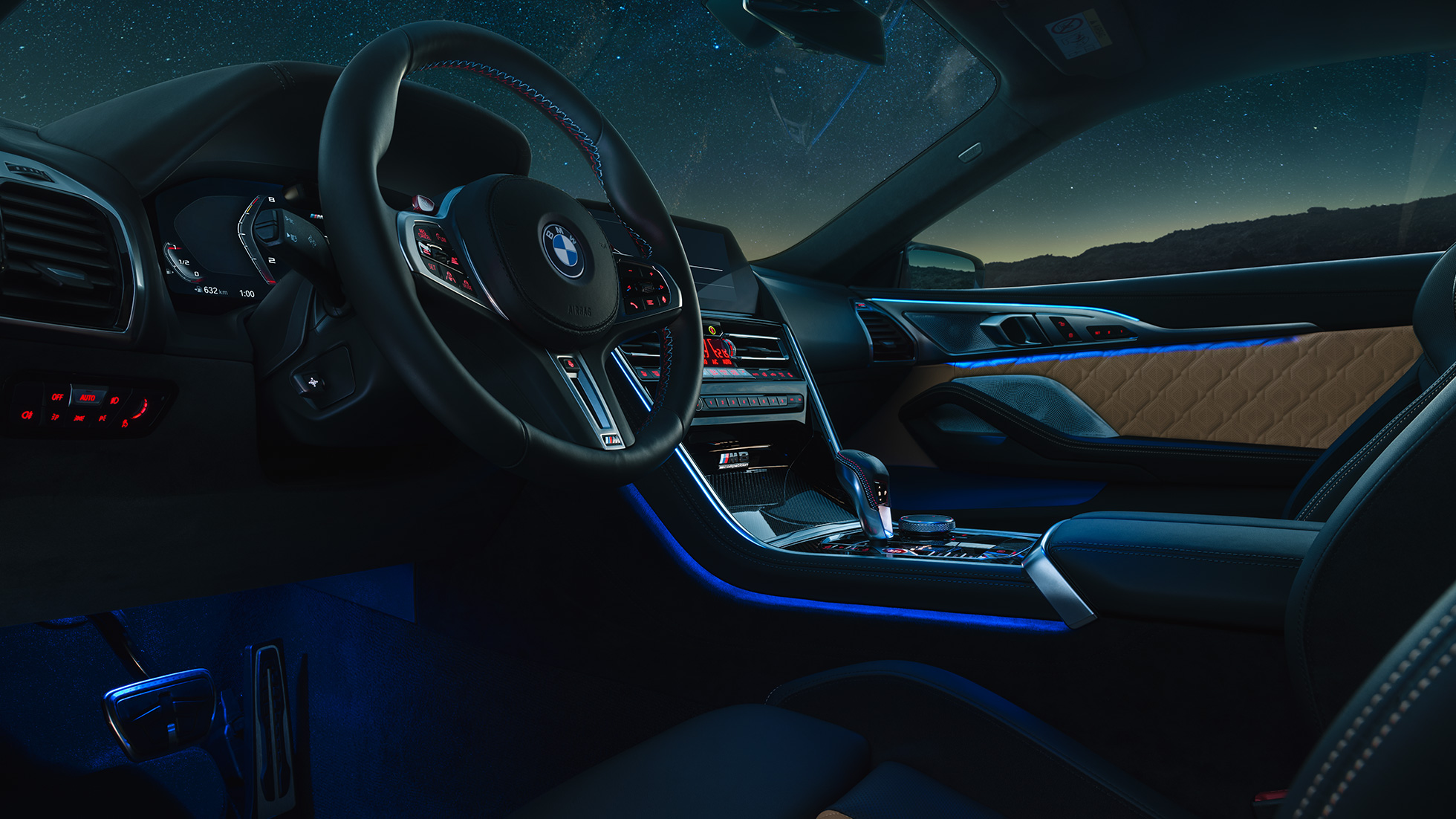 BMW M8 Competition Coupé, кабина. BMW M8 Competition Coupé, кабина ночью с кожаным рулевым колесом M и синим фоновым освещением.