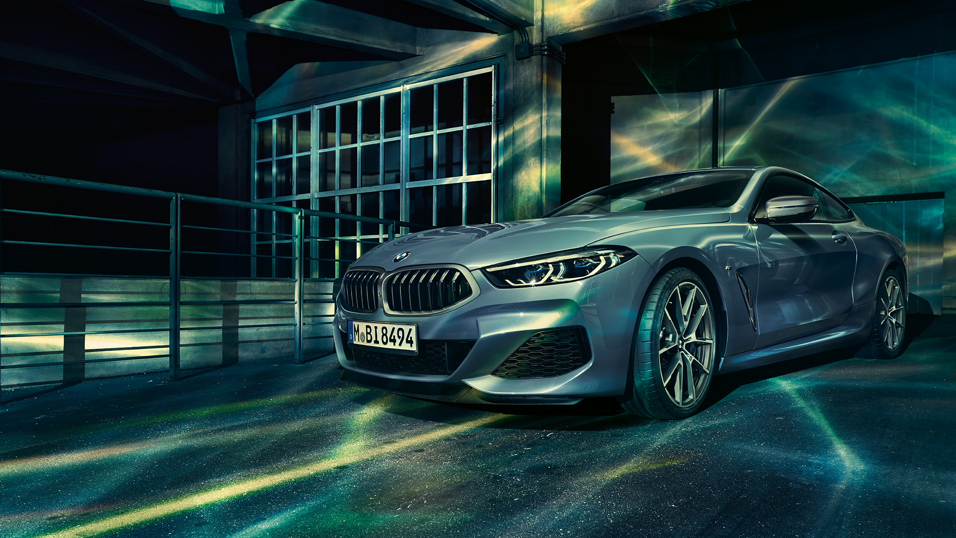 BMW M850i xDrive Coupé, вид спереди с поворотом в три четверти. BMW M850i xDrive Coupé в Barcelona Blue металлик, вид спереди с поворотом в три четверти, перед зданием.
