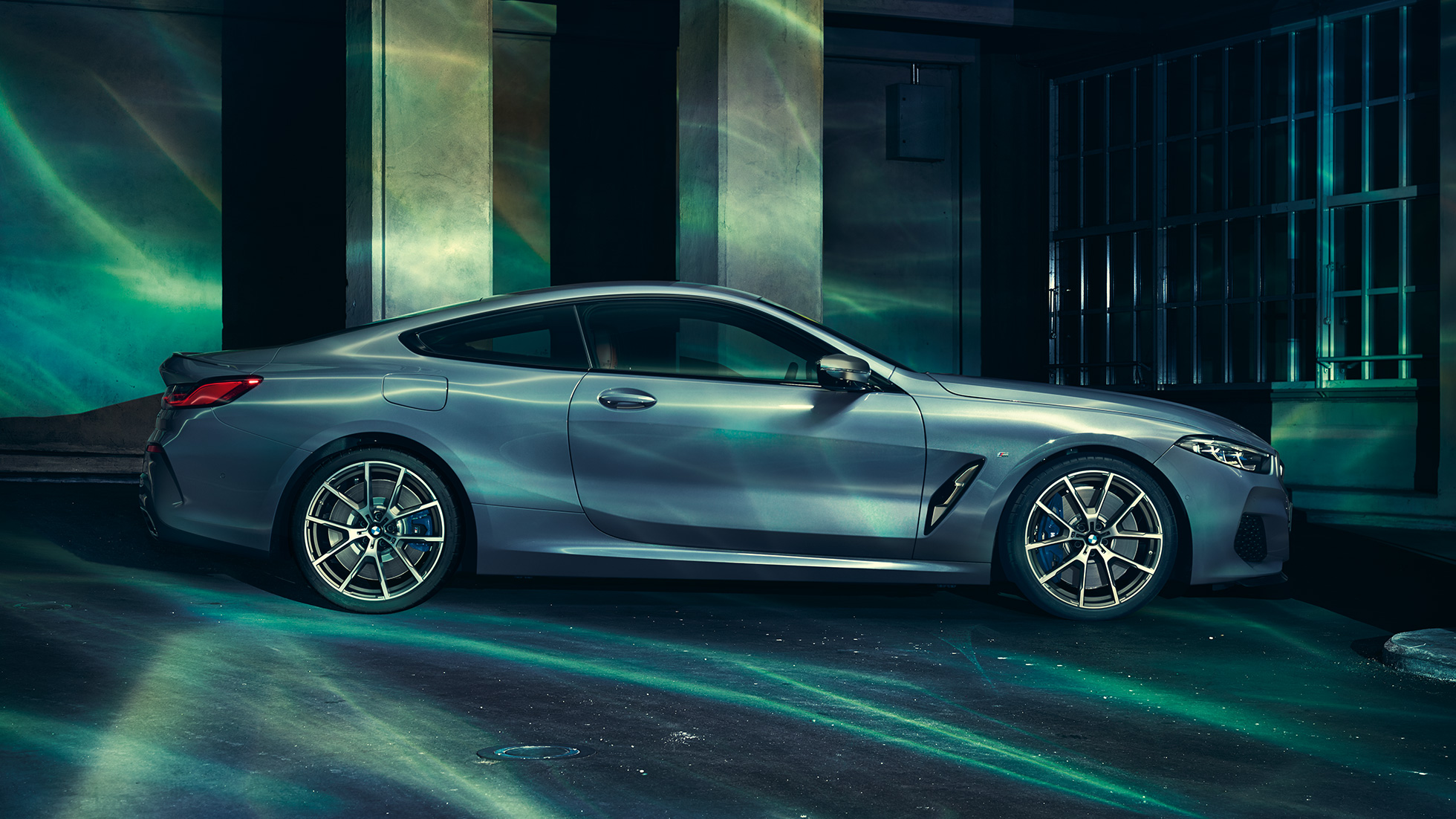 BMW M850i xDrive Coupé, вид сбоку. BMW M850i xDrive Coupé в Barcelona Blue металлик, вид сбоку, перед зданием.