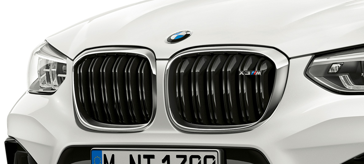 BMW X3 M, решетка радиатора М. BMW X3 M в Alpine White, экстерьер, передняя часть, решетка радиатора M с хромированными вставками и обозначением модели.