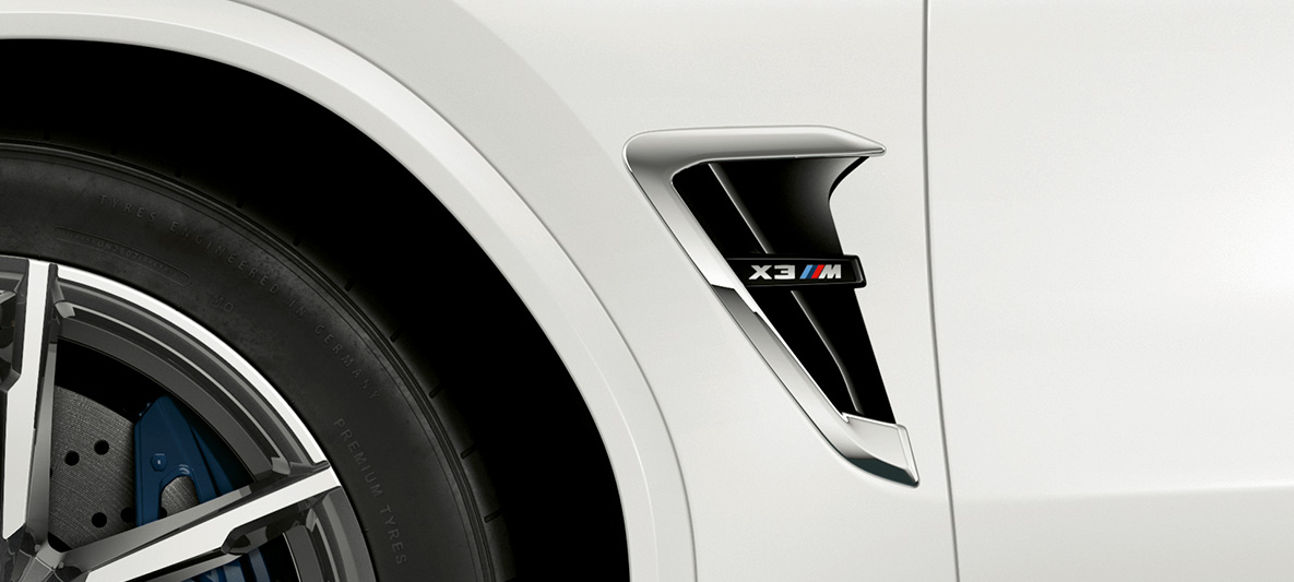 BMW X3 M, жабры M. BMW X3 M в Alpine White, экстерьер, жабры M с хромированными вставками и обозначением модели.