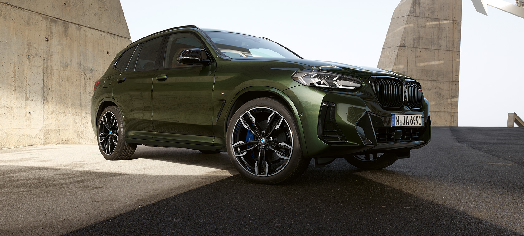 BMW X3 M40i G01 LCI 2021 Facelift, вид спереди в три четверти на месте BMW X3 M F97 LCI Facelift 2021 в цвете Malachite Green металлик, вид спереди в три четверти на месте