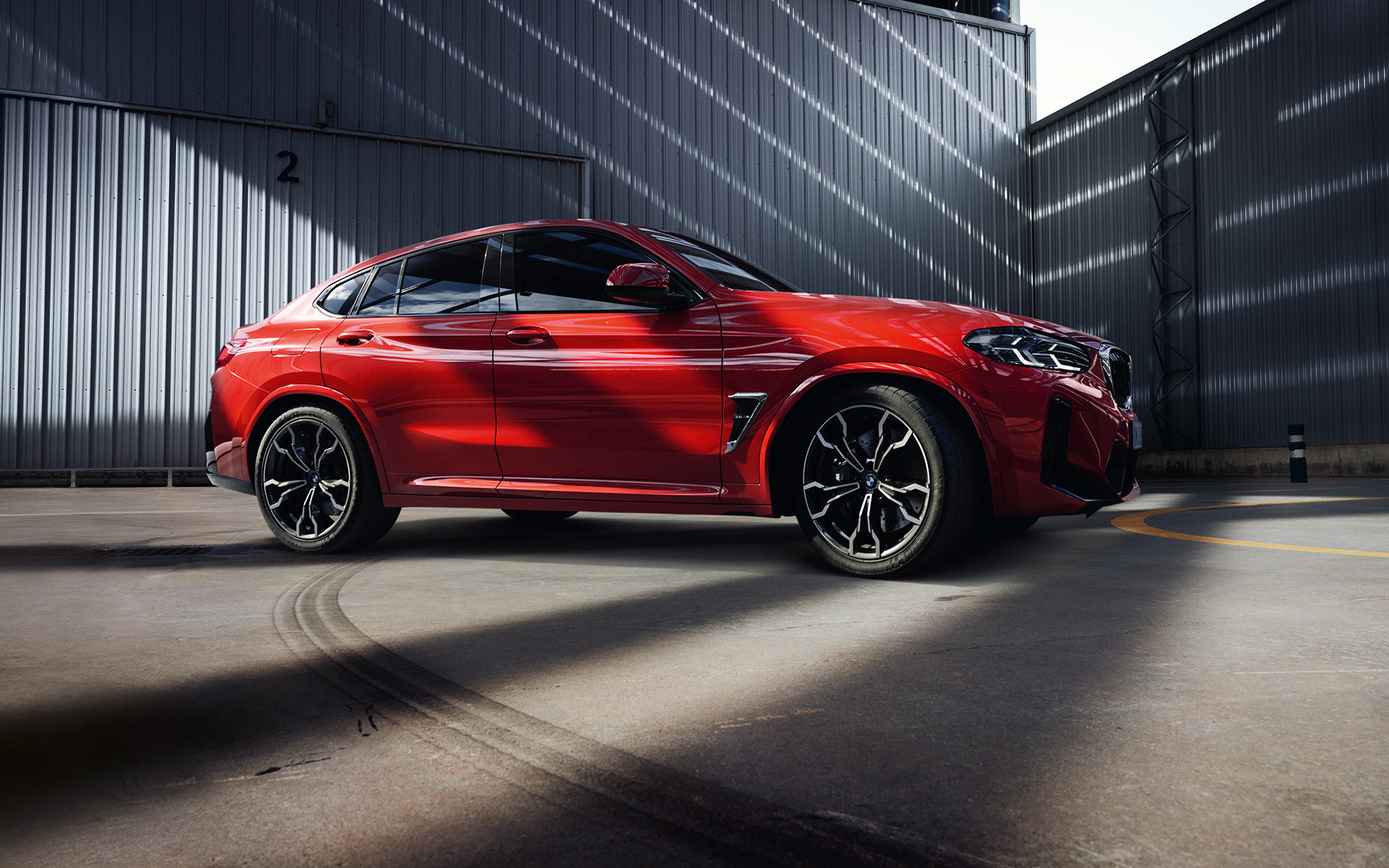 BMW X4 M F98 LCI Facelift 2021 в цвете Toronto Red металлик, вид сбоку в три четверти перед фабрикой