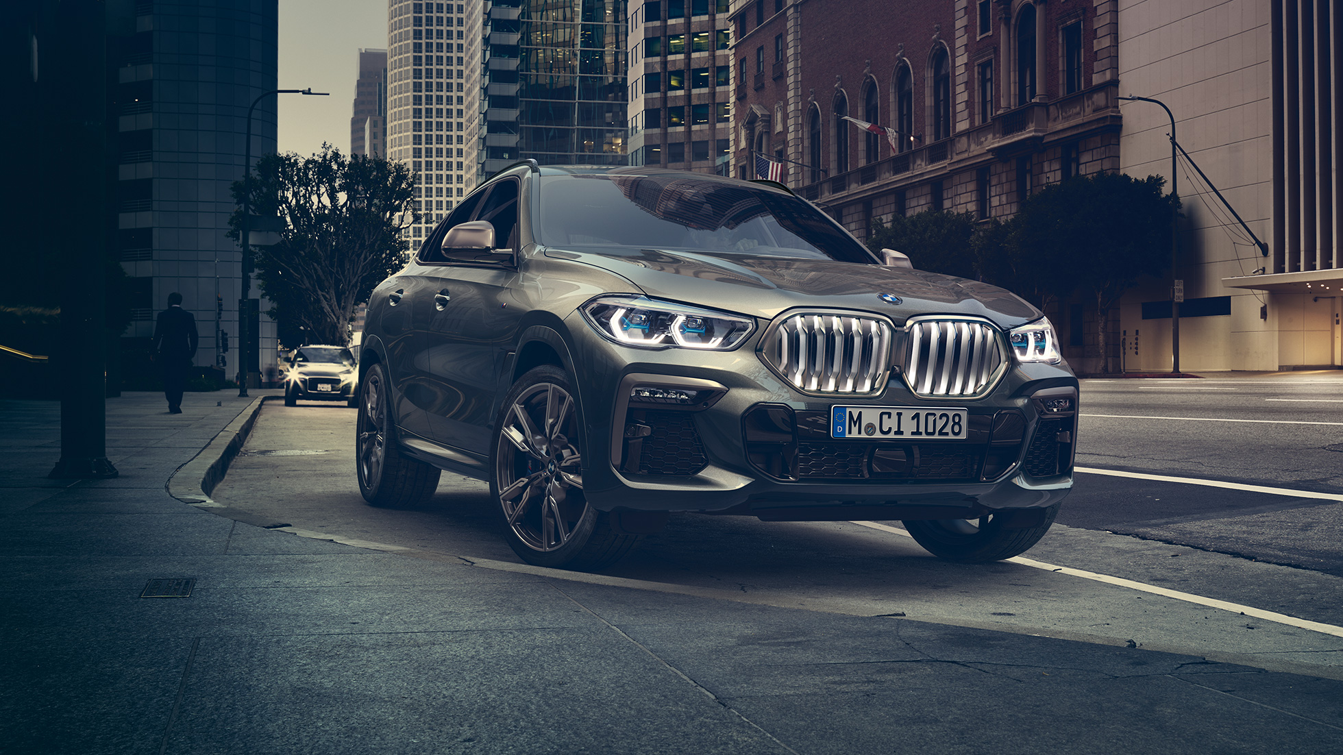 Адаптивная подвеска BMW X6 M Professional. BMW X6, передняя часть с поворотом в три четверти перед городской обстановкой.