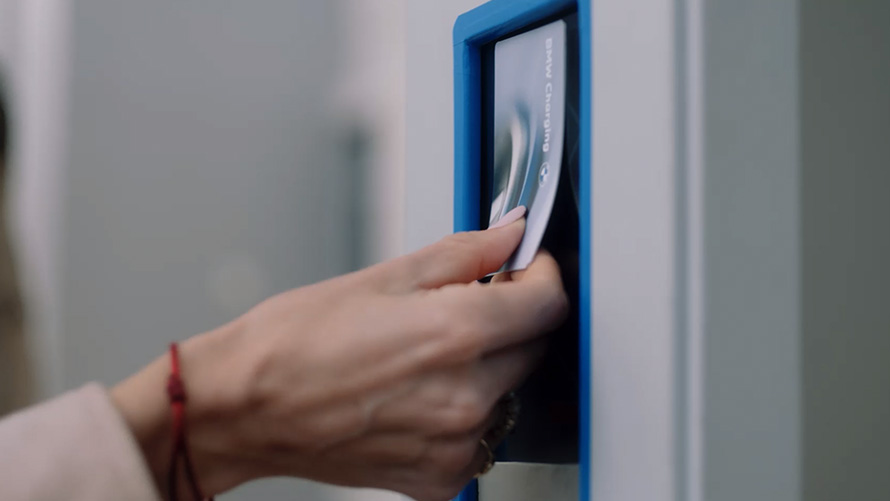 Человек использует карту BMW Charging на общественной зарядной станции Человек использует карту BMW Charging на общественной зарядной станции