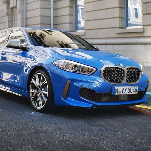 BMW 1 серии, вид спереди с поворотом в три четверти на обочине. BMW 1 серии в цвете Misano Blue металлик, вид спереди с поворотом в три четверти, парковка на обочине.